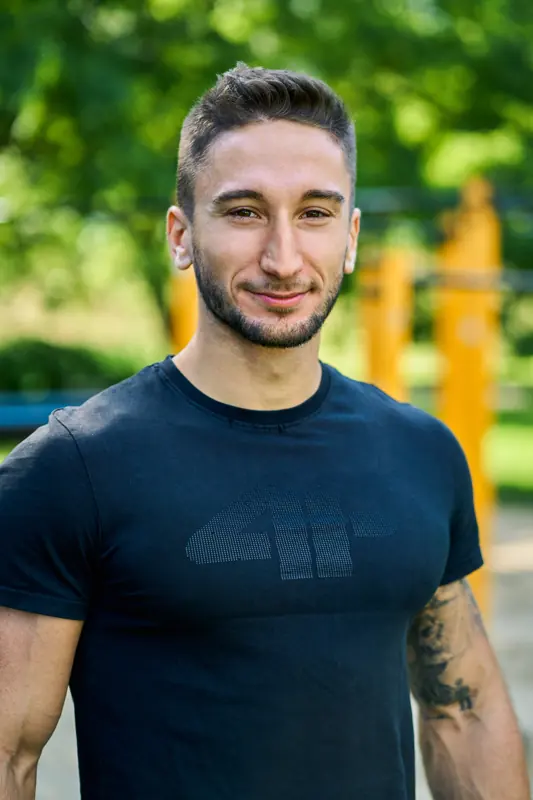 Patryk Wygadańczuk uśmiecha się w parku street workout